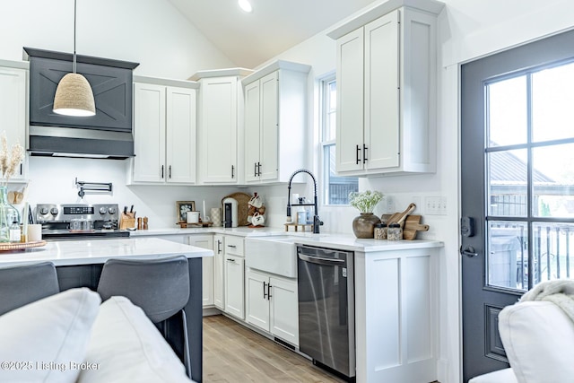 kitchen with sink, hanging light fixtures, light wood-type flooring, appliances with stainless steel finishes, and white cabinetry