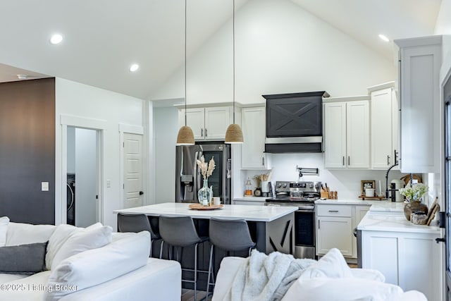 kitchen with high vaulted ceiling, a kitchen island, hanging light fixtures, and appliances with stainless steel finishes