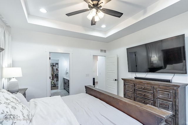 bedroom featuring connected bathroom, a tray ceiling, and ceiling fan