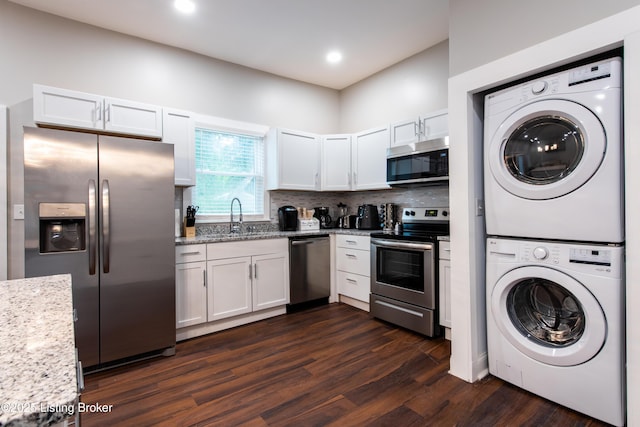 kitchen featuring white cabinetry, sink, stacked washer and dryer, and stainless steel appliances