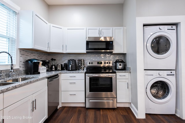 kitchen featuring stacked washer and dryer, white cabinets, stainless steel appliances, and sink