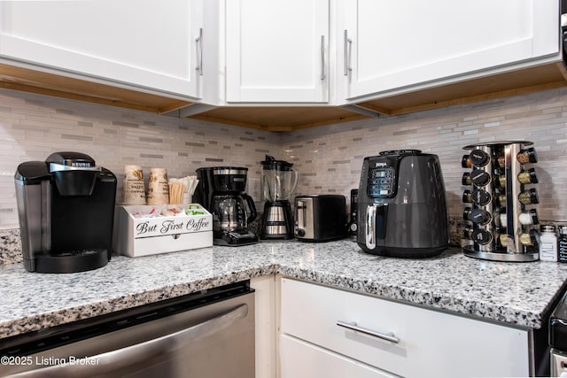 room details featuring dishwasher, backsplash, white cabinets, and light stone counters