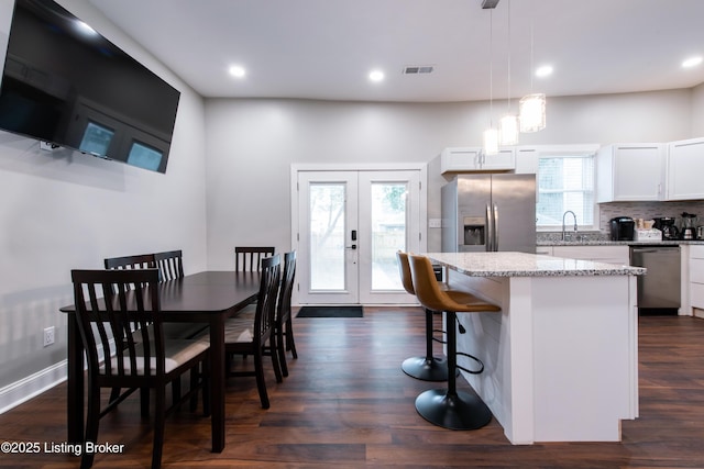 kitchen featuring pendant lighting, white cabinets, dark hardwood / wood-style floors, appliances with stainless steel finishes, and a kitchen island