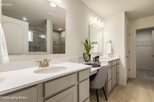 bathroom featuring wood-type flooring, vanity, and a tile shower