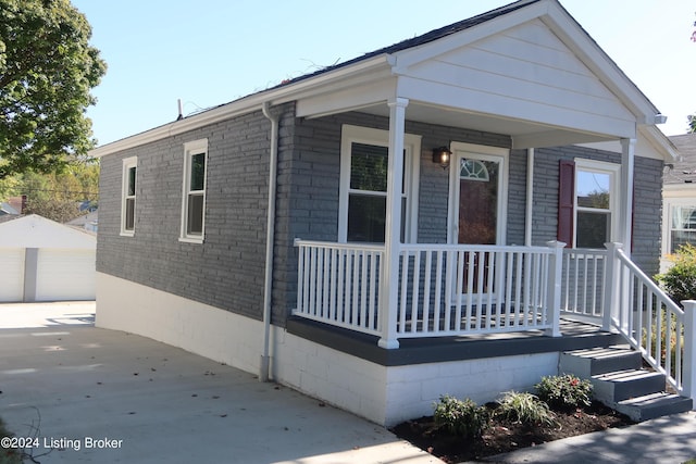 view of front of home featuring covered porch, a garage, and an outbuilding