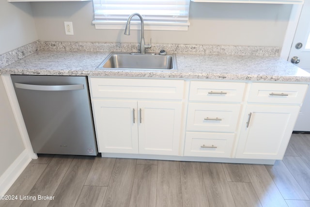 kitchen with stainless steel dishwasher, light stone counters, white cabinetry, and sink