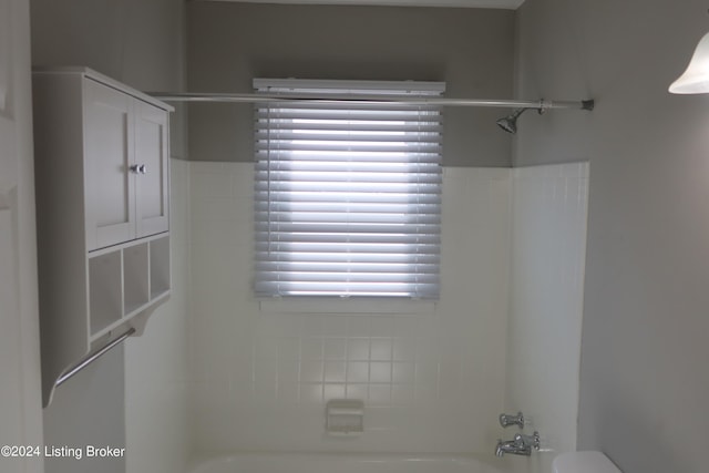 bathroom featuring tiled shower / bath combo and toilet