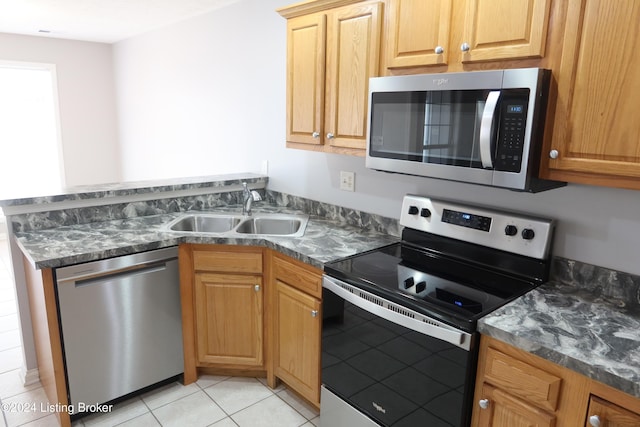 kitchen with dark stone countertops, sink, light tile patterned floors, and appliances with stainless steel finishes