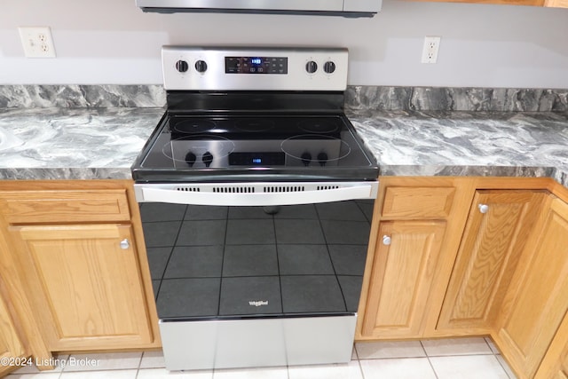 kitchen featuring stainless steel electric range, light brown cabinets, and light tile patterned floors