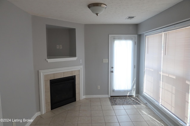 foyer entrance with plenty of natural light, light tile patterned floors, a textured ceiling, and a tiled fireplace