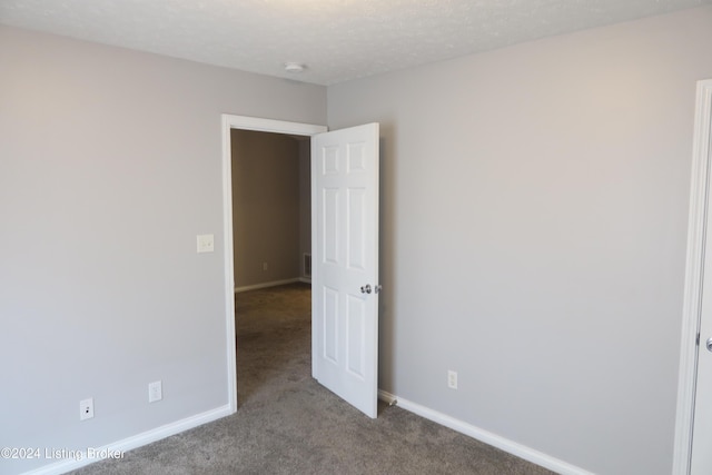 unfurnished room featuring a textured ceiling and light carpet