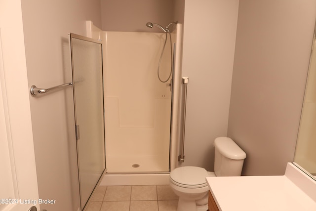 bathroom featuring tile patterned flooring, vanity, toilet, and a shower with door