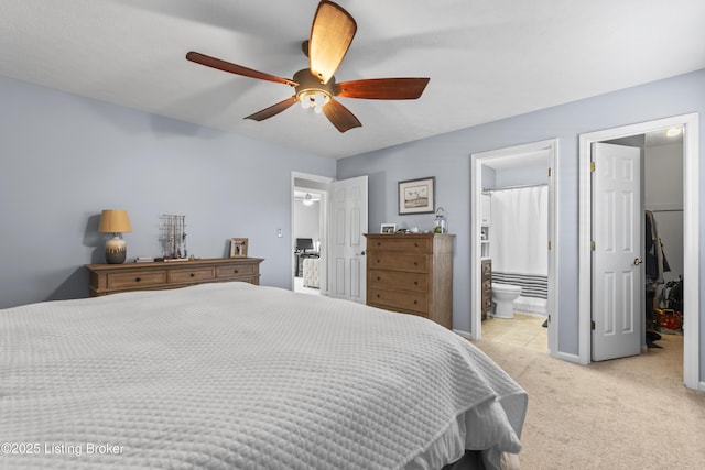 bedroom with connected bathroom, ceiling fan, light colored carpet, and a walk in closet