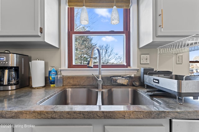 interior details with white cabinetry, sink, and pendant lighting