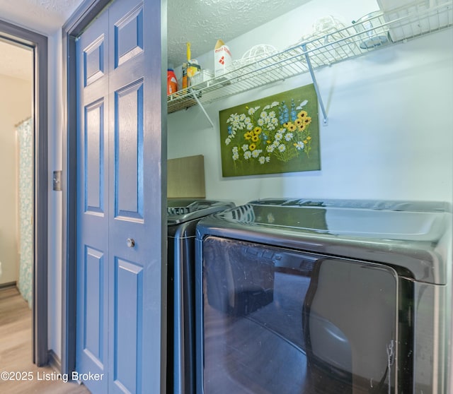 laundry room with washer and clothes dryer, wood-type flooring, and a textured ceiling