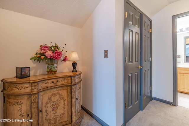 corridor featuring light colored carpet and vaulted ceiling