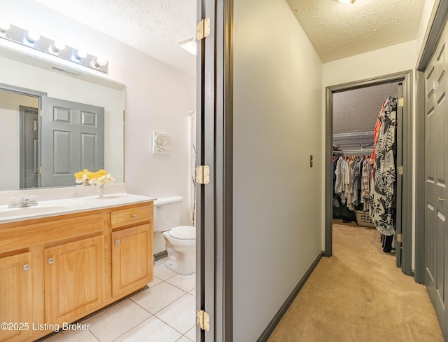 bathroom featuring vanity, tile patterned floors, a textured ceiling, and toilet