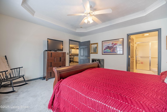 bedroom featuring ensuite bathroom, carpet flooring, ceiling fan, ornamental molding, and a tray ceiling