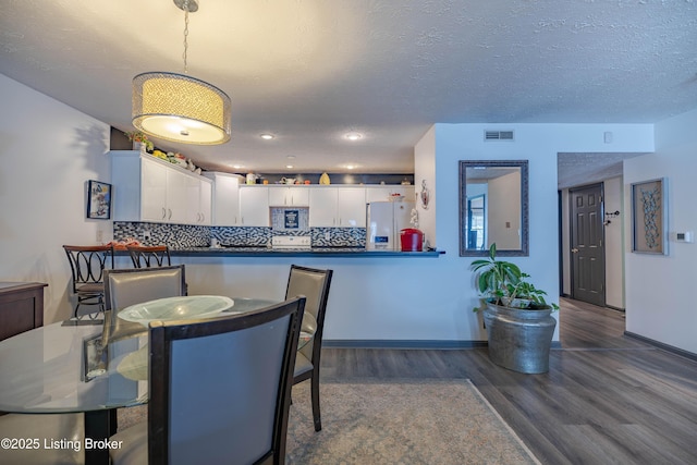 dining room with a textured ceiling and dark hardwood / wood-style floors