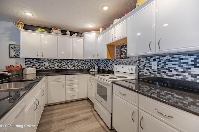 kitchen featuring white appliances, dark stone counters, white cabinets, sink, and a textured ceiling