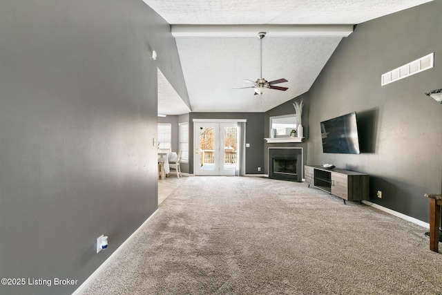 unfurnished living room featuring beam ceiling, ceiling fan, french doors, a textured ceiling, and light carpet