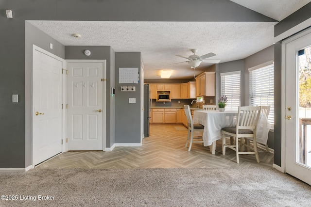 dining room featuring ceiling fan, sink, light parquet floors, and a textured ceiling