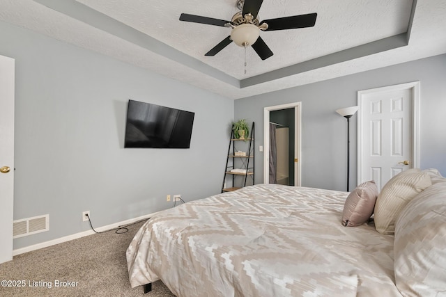 carpeted bedroom with a tray ceiling and ceiling fan