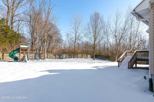 snowy yard featuring a playground