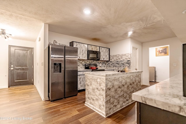 kitchen with decorative backsplash, stainless steel refrigerator with ice dispenser, and light hardwood / wood-style flooring