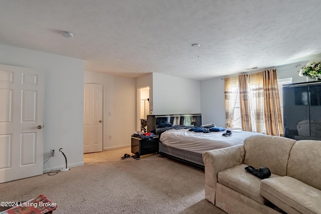 bedroom with light colored carpet and a textured ceiling