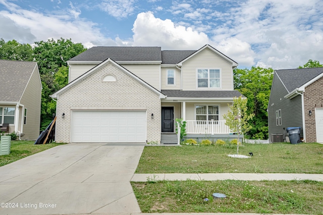 view of front of home with a front yard, a porch, central AC, and a garage