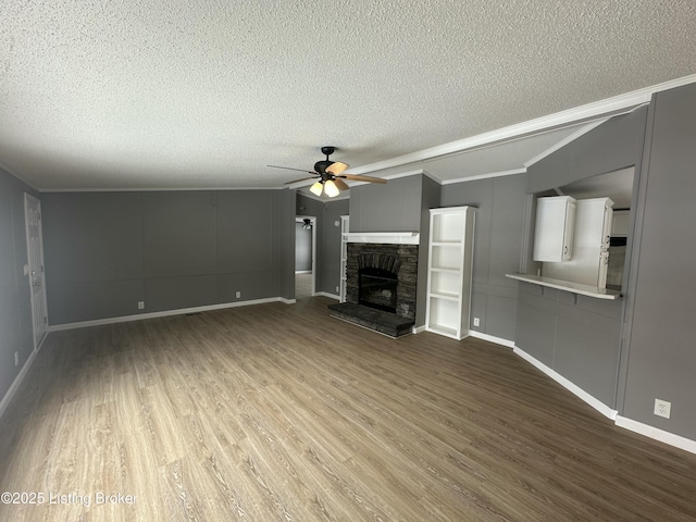 unfurnished living room featuring ceiling fan, hardwood / wood-style floors, a textured ceiling, a fireplace, and ornamental molding