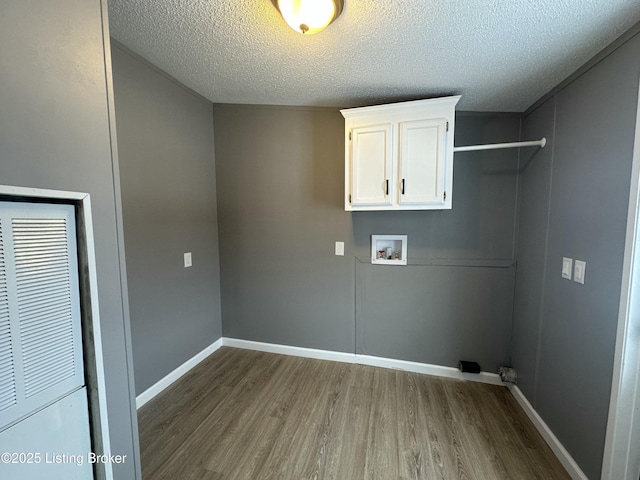 clothes washing area featuring wood finished floors, a heating unit, cabinet space, baseboards, and hookup for a washing machine