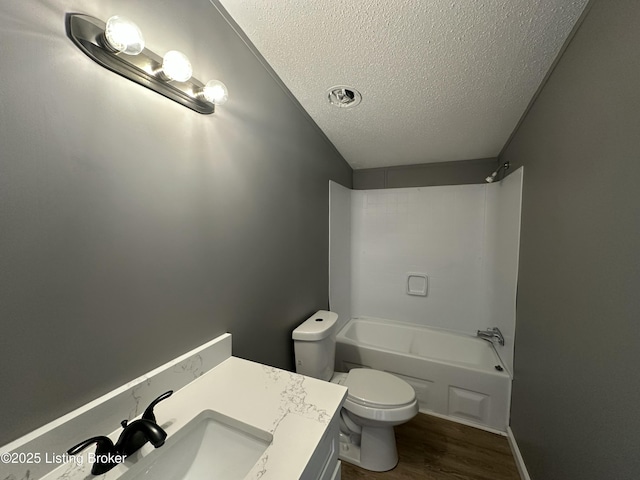 bathroom featuring toilet, a textured ceiling, shower / washtub combination, wood finished floors, and vanity