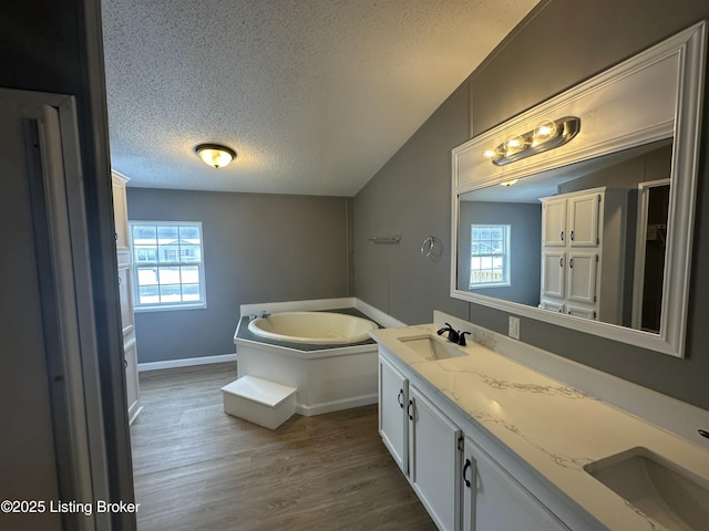 full bathroom featuring a sink, a textured ceiling, and a healthy amount of sunlight