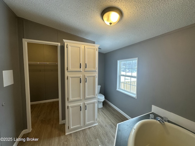 full bath featuring a washtub, toilet, lofted ceiling, wood finished floors, and a textured ceiling