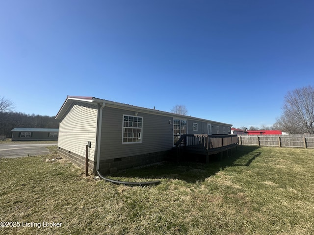 rear view of house with crawl space, a lawn, a wooden deck, and fence