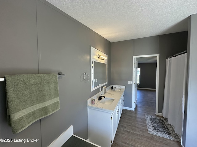 bathroom featuring double vanity, wood finished floors, a textured ceiling, and a sink