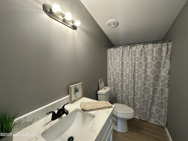 bathroom featuring vanity, wood finished floors, lofted ceiling, a textured ceiling, and toilet