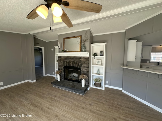 unfurnished living room featuring a decorative wall, a stone fireplace, crown molding, and wood finished floors