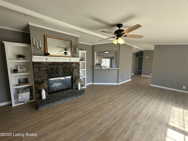 unfurnished living room featuring crown molding, ceiling fan, a fireplace, wood finished floors, and a textured ceiling