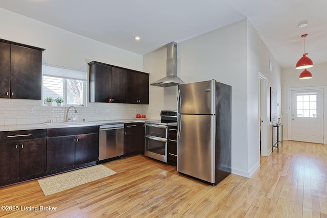 kitchen with decorative light fixtures, wall chimney range hood, dark brown cabinetry, and stainless steel appliances