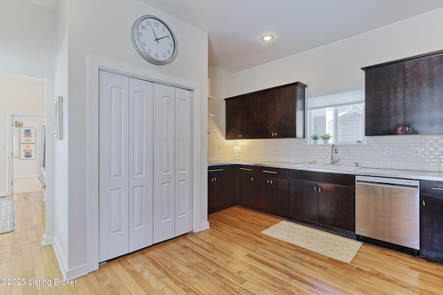 kitchen with light hardwood / wood-style floors, tasteful backsplash, dark brown cabinets, dishwasher, and sink