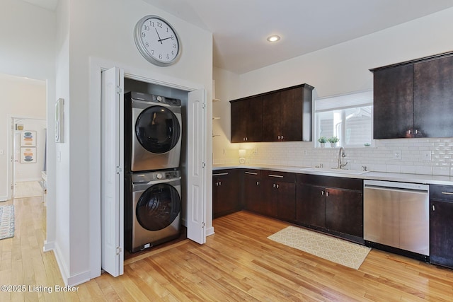 laundry area featuring sink, stacked washer and clothes dryer, and light hardwood / wood-style flooring