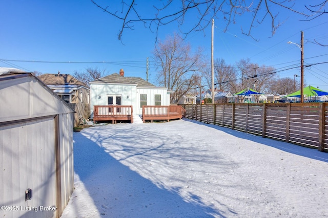 yard covered in snow with a deck and an outdoor structure