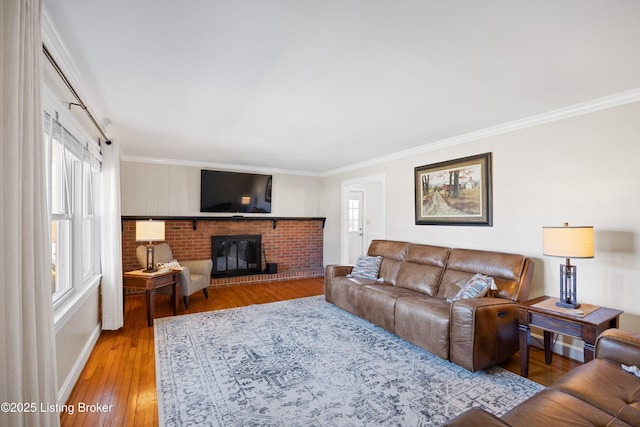 living room with wood-type flooring, a brick fireplace, and crown molding