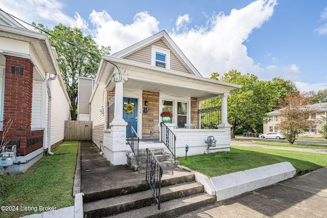 bungalow-style home featuring covered porch and a front yard