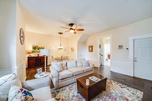 living room with ceiling fan with notable chandelier and dark hardwood / wood-style floors