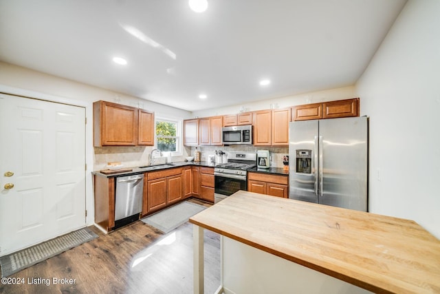 kitchen with sink, light hardwood / wood-style flooring, appliances with stainless steel finishes, tasteful backsplash, and butcher block countertops