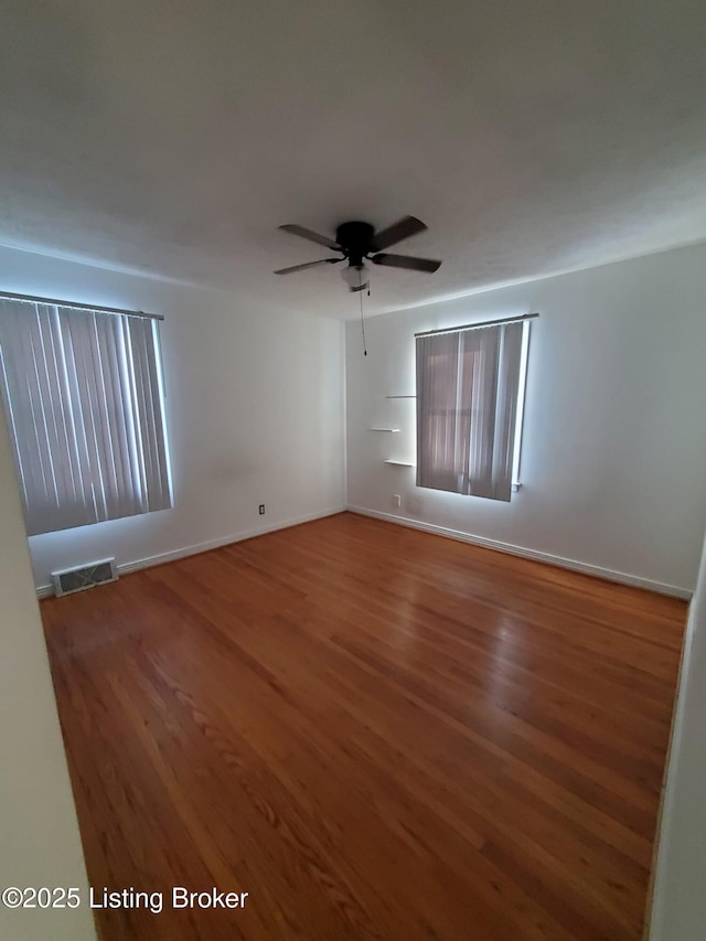 empty room featuring ceiling fan, a wealth of natural light, and hardwood / wood-style floors